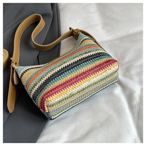 Close-up detail of the colorful rainbow woven texture and brown leather strap on the bag