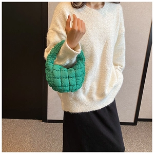 Close-up of vibrant green quilted bubble handbag styled with a white knitted sweater