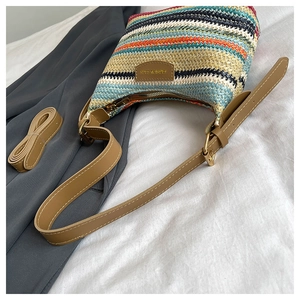 Close-up of rainbow woven shoulder bag with brown leather strap and metal zipper detail