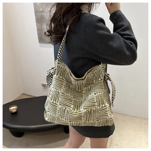 Detail view of olive green knit tote bag featuring geometric patterns and polka dot strap