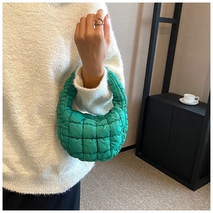 Detail of green quilted cloud bag showing the puffy nylon texture and integrated handle