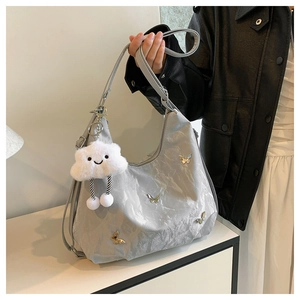Détail du sac hobo gris avec papillon, charme nuage pelucheux et sangle ajustable