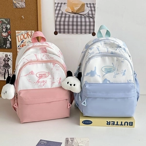 Close-up of nylon backpacks with mountain prints and cute panda plush charms