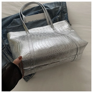 Detail of silver crocodile-embossed tote bag with metallic leather texture and handles