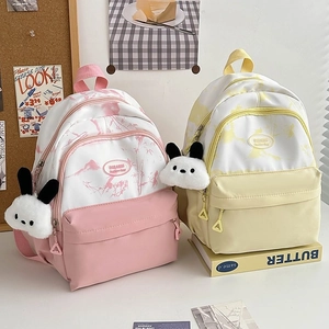 Close-up of nylon backpacks in pink and yellow with cute rabbit charms for students