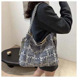Detail of blue geometric woven tote bag featuring polka dot bow and wide shoulder strap