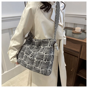 Detail view of canvas crossbody bag showing abstract geometric patterns and knotted strap