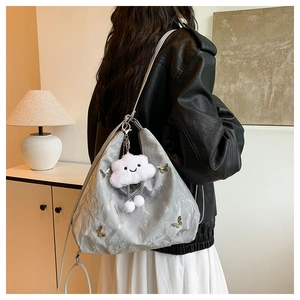 Détail du sac cabas argenté avec texture froissée, breloque papillon et pendentif nuage