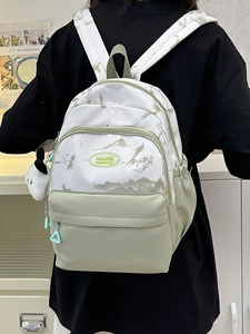 Detail of minimalist nylon backpack showing landscape print and cute dog charm accessory