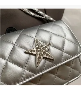 Détail d'un sac bandoulière argenté matelassé avec une étoile scintillante en strass
