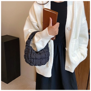 Detail of black quilted cloud bag showing puff texture on model in minimalist setting