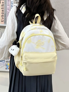 Detailed view of yellow and white nylon backpack with panda plush charm and brand label