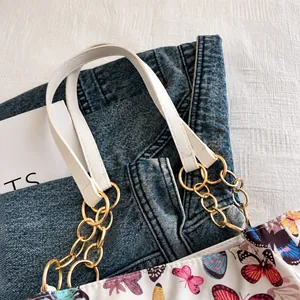 Detail of white faux leather handle with gold metal chain rings on butterfly tote bag