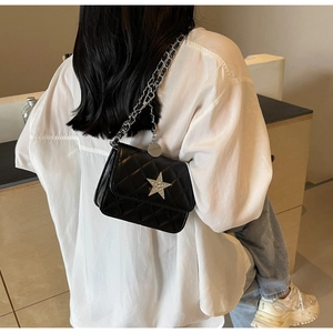 Détail du sac à bandoulière noir matelassé avec fermoir étoile brillant et bandoulière chaîne