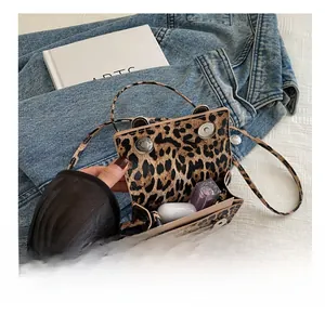 Détails intérieurs du mini sac léopard montrant la capacité avec rouge à lèvres et écouteurs