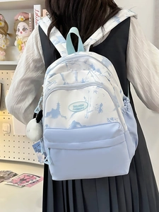 Detail of light blue nylon backpack featuring a mountain landscape print and plush charm