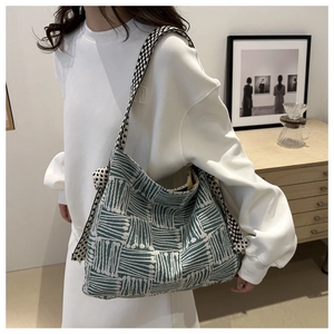 Close-up of oversized knitted tote bag with blue geometric patterns and checkered strap