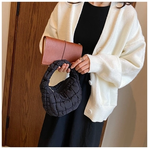 Detail of black quilted cloud bag showing the puffy handle and textured nylon fabric on model