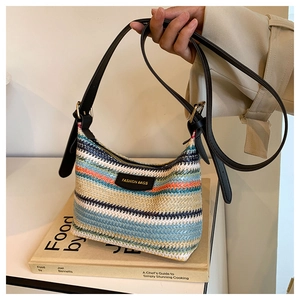 Detailed close-up of rainbow straw woven bag with leather brand patch and gold zipper