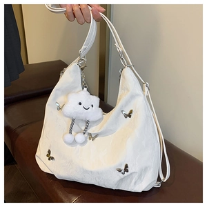 Close-up of white crossbody bag with silver butterfly buckles and fluffy cloud charm accessory