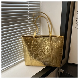 Detailed view of golden crocodile-embossed tote bag with metallic luster finish