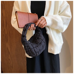 Detail of black quilted cloud bag with puffy lattice stitching and crescent handle