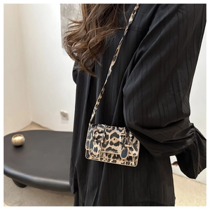 Détail du mini sac bandoulière léopard avec deux boucles décoratives et fermeture à rabat
