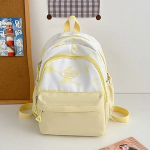 Close-up of a nylon backpack featuring a logo patch and a cream-yellow patchwork design