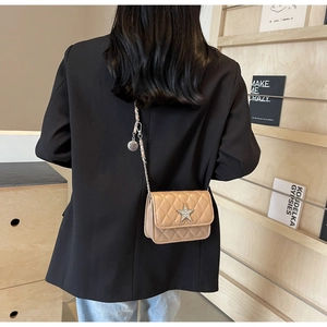Détail d'un sac bandoulière matelassé beige avec strass en forme d'étoile sur manteau noir