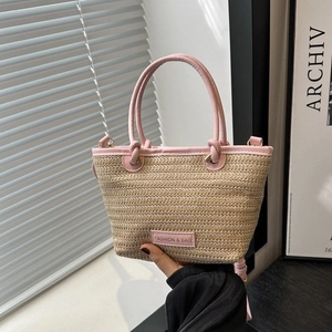Détail d'un sac à main en paille tressée avec poignée en cuir rose à la main