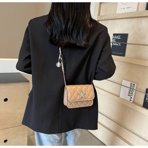 Petit sac à bandoulière matelassé beige avec étoile sur un blazer noir vue de dos