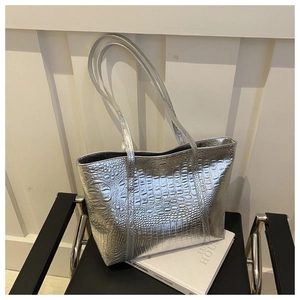 Close-up of silver tote bag with crocodile texture on a black minimalist chair
