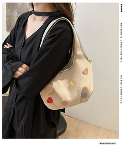 Gros plan du sac à bandoulière en cuir crème avec des écussons en forme de cœur