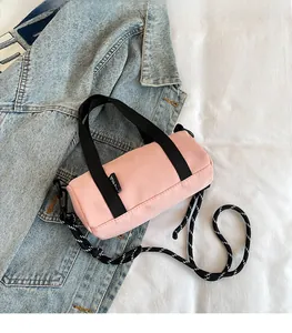 Sac cylindrique rose avec poignées en sangle noires et bandoulière en corde à motifs