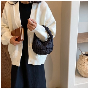 Detailed view of black quilted puffy cloud bag with soft nylon texture and handle