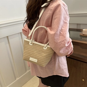 Détail du sac cabas en paille tressée beige avec anses en cuir blanc et bandoulière réglable