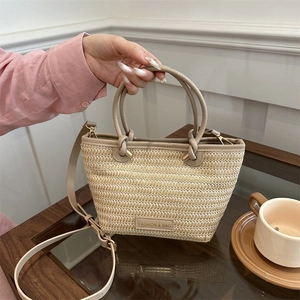 Détail du sac cabas tissé avec poignées en similicuir et logo mode sur table en bois