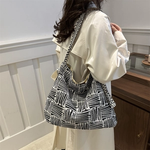 Canvas tote bag with black and white geometric patterns on a trench coat model