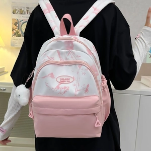 Detail of pink and white nylon backpack with ink-wash pattern and plush bunny pendant
