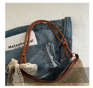 Detail shot of woven straw bag with brown leather handles and cream lace bow accents