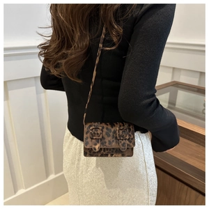 Détail d'un mini sac bandoulière à motif léopard avec deux boucles vintage sur le rabat