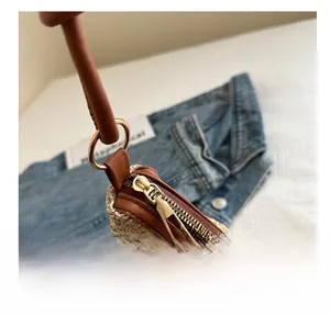 Detail of premium straw beach bag showing smooth golden zipper and brown leather trim
