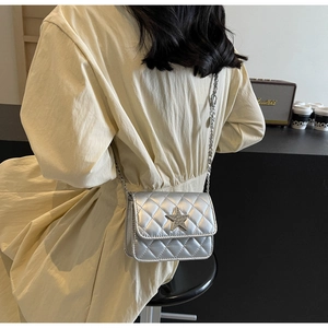 Sac bandoulière argenté matelassé avec étoile à paillettes porté par un mannequin