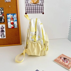 Detail view of the nylon backpack showing its side elastic pocket and pastel yellow pattern