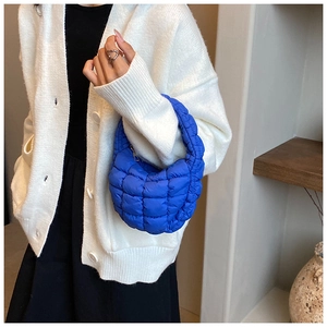 Macro detail of vibrant blue puffy quilted handbag showing square stitching patterns