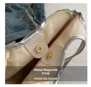 Détail du fermoir magnétique doré sur le sac fourre-tout argenté avec doublure en tissu