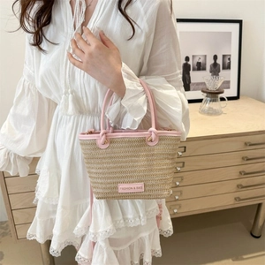 Détail du sac cabas en paille tressée avec anses en similicuir rose et logo de mode