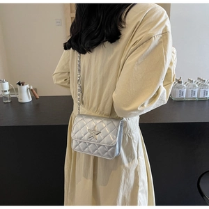 Détail d'un sac bandoulière argenté matelassé avec étoile en strass sur un mannequin