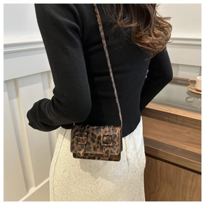 Détail du mini sac bandoulière léopard avec boucles vintage et rabat texturé élégant