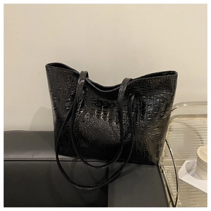 Close-up of black crocodile pattern embossing on large tote bag with glossy finish